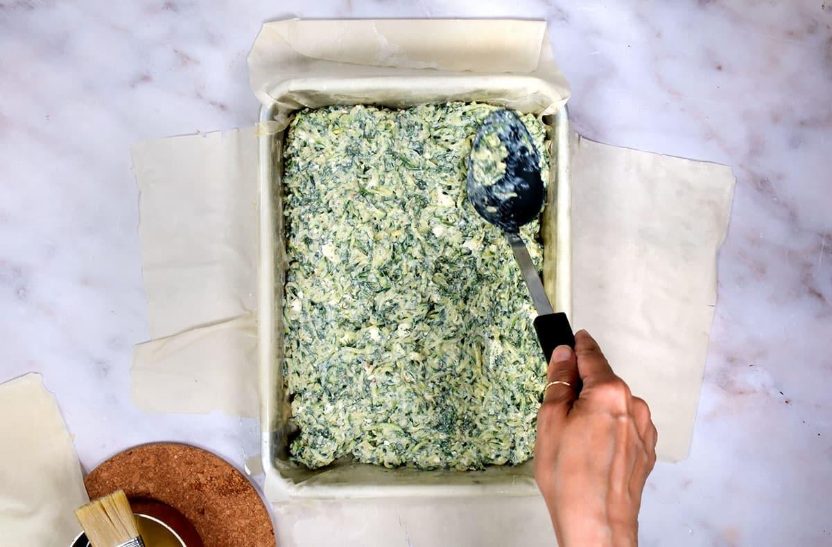 assembling kolokithopita - greek phyllo pie with courgettes and feta