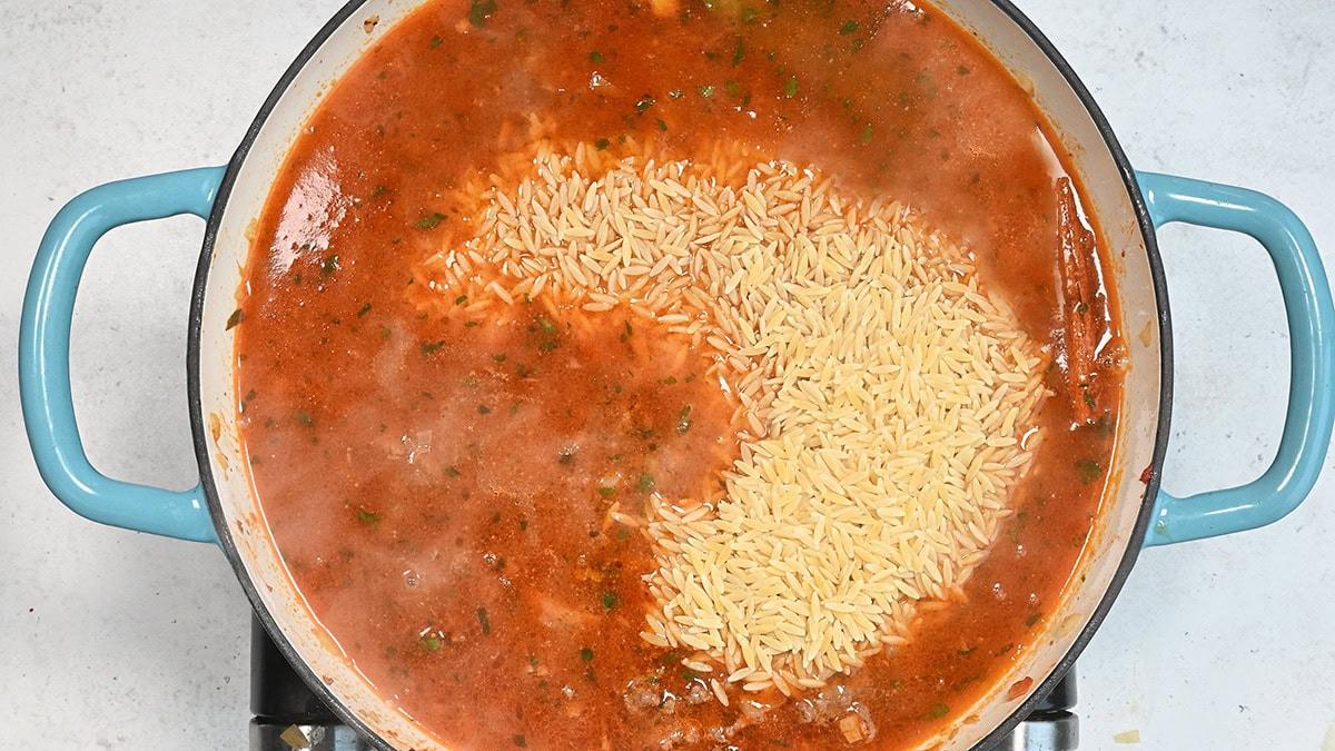 orzo cooking in chicken broth with ground beef and tomato paste