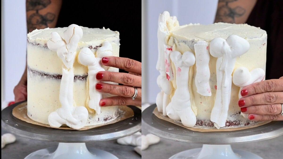 Hands applying meringue bones to the side of a white frosted cake.