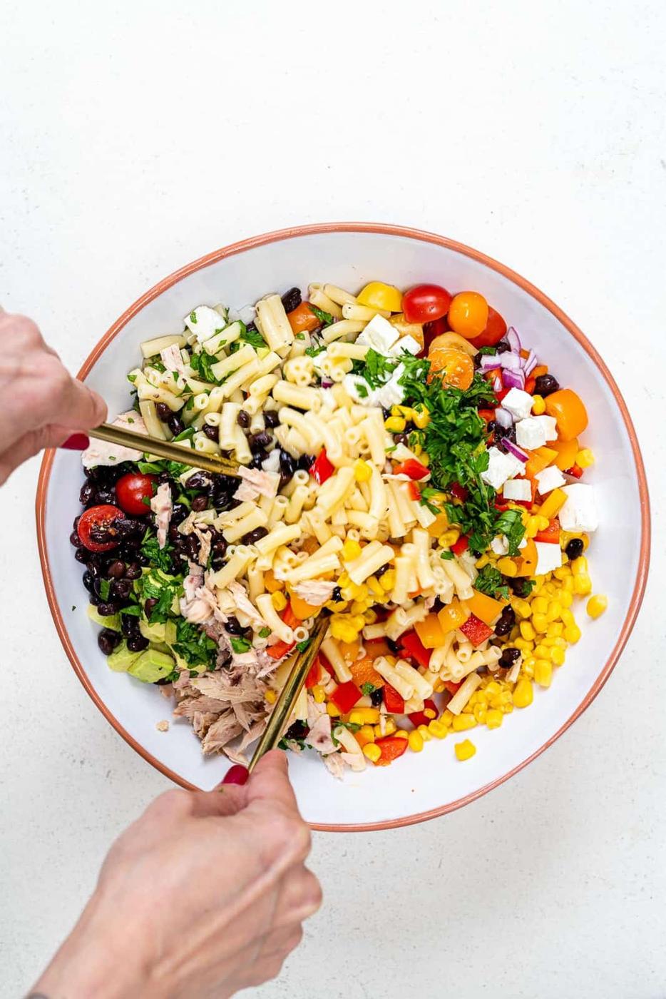 tossing tuna pasta salad in a bowl
