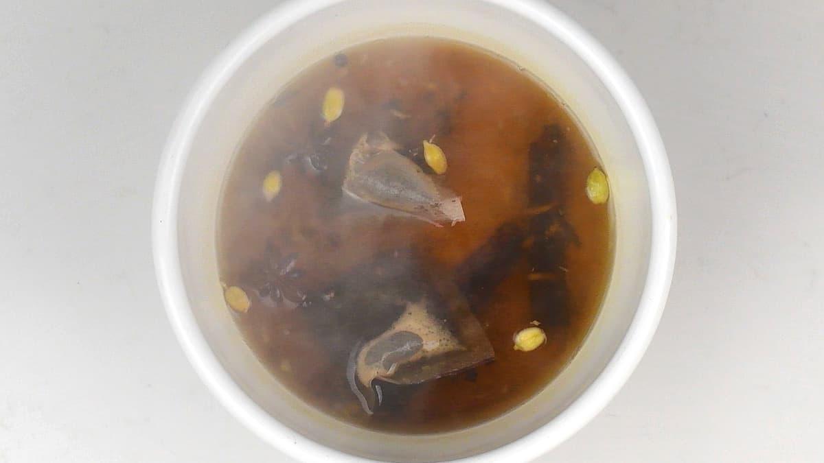 steeping tea bags in hot water and spices to make chai masala