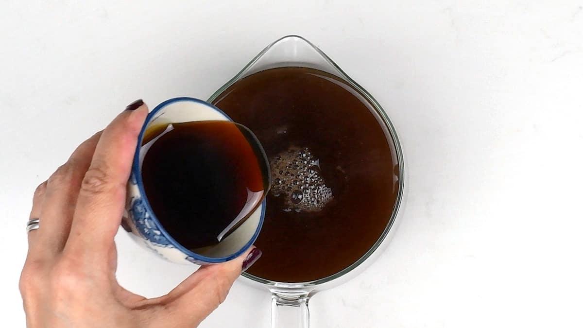 adding maple syrup to a pot of chai tea