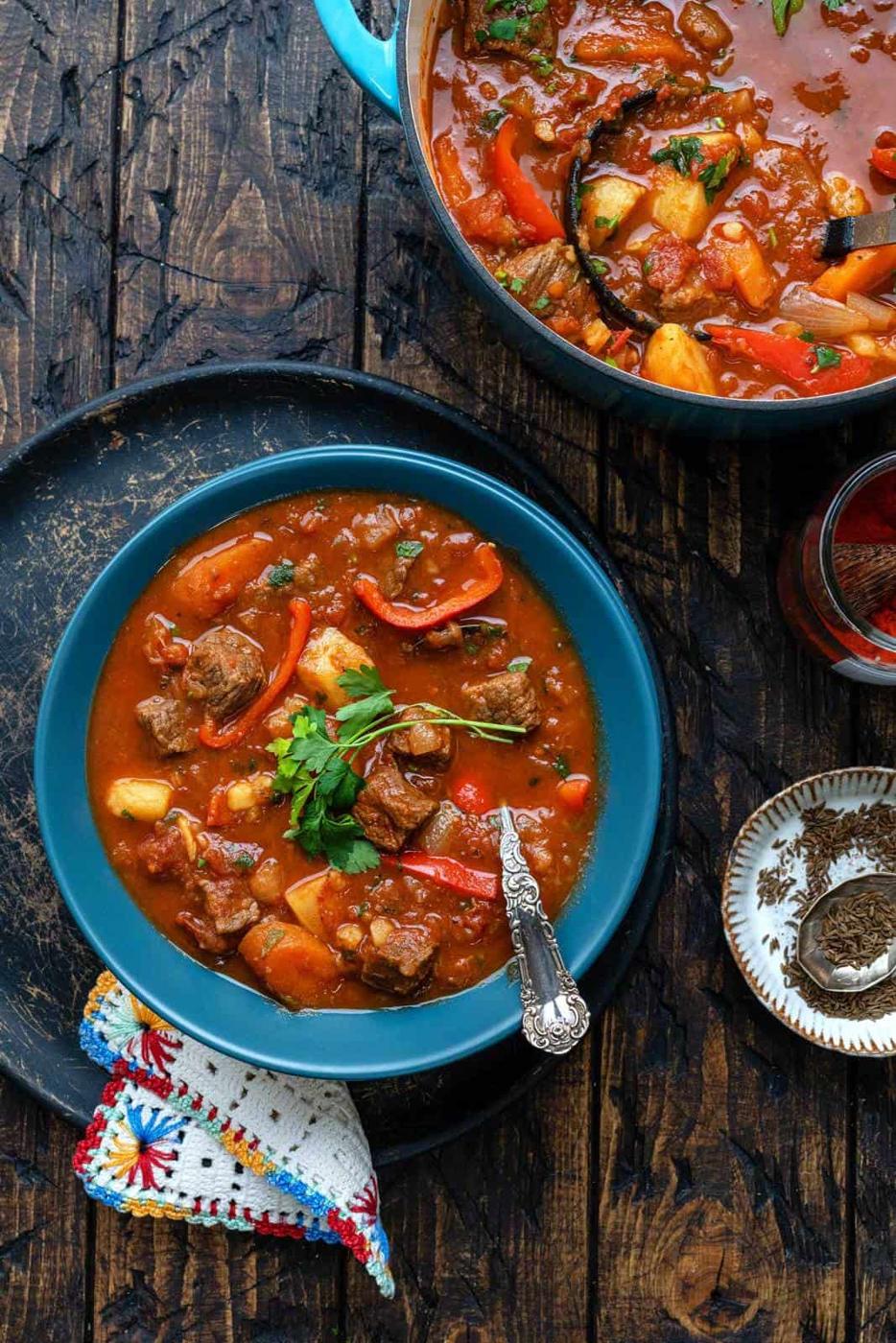 Hungarian goulash served in a blue bowl with parsley