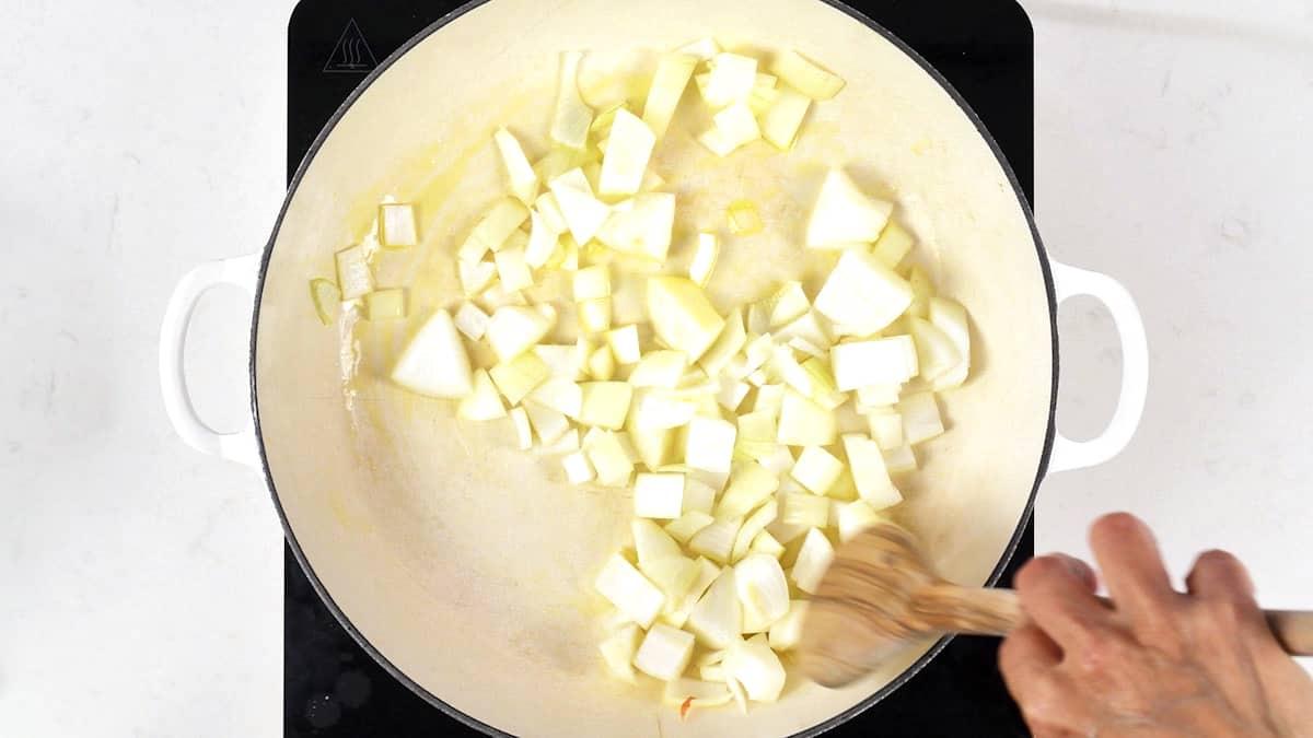 Diced onions softening in a cast iron casserole dish for goulash