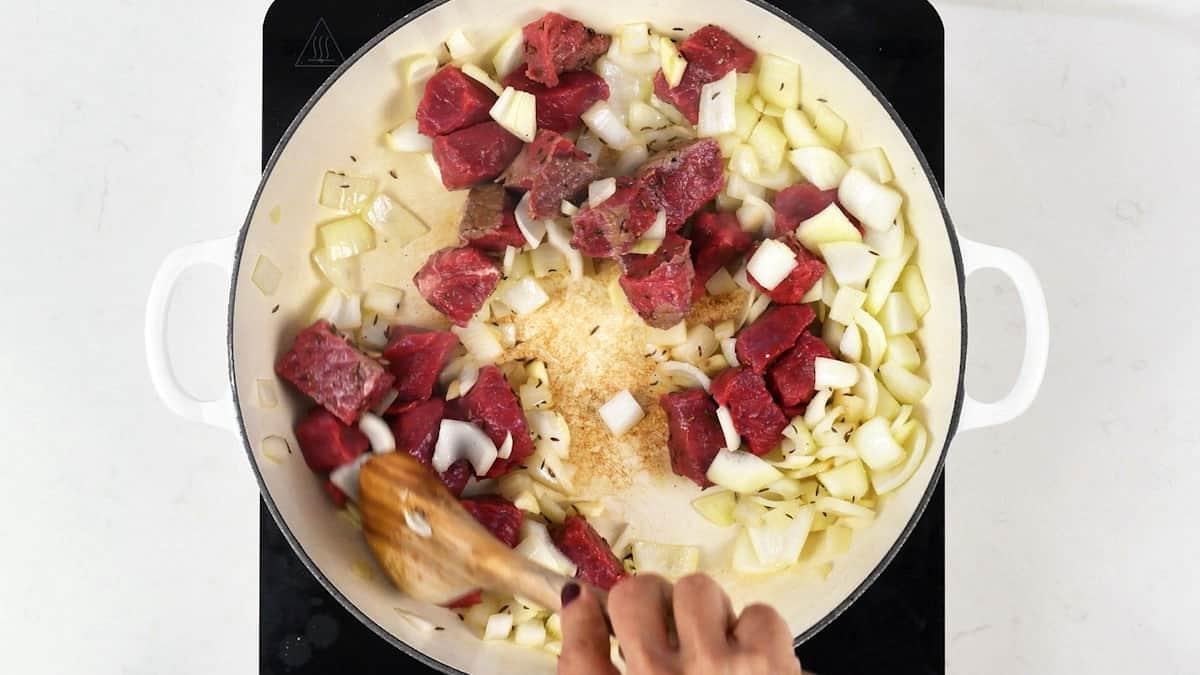 Browning cubes of beef with onions and caraway seeds