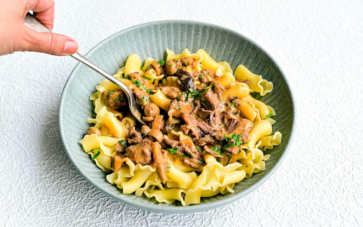 Bowl of beef stroganoff served over noodles