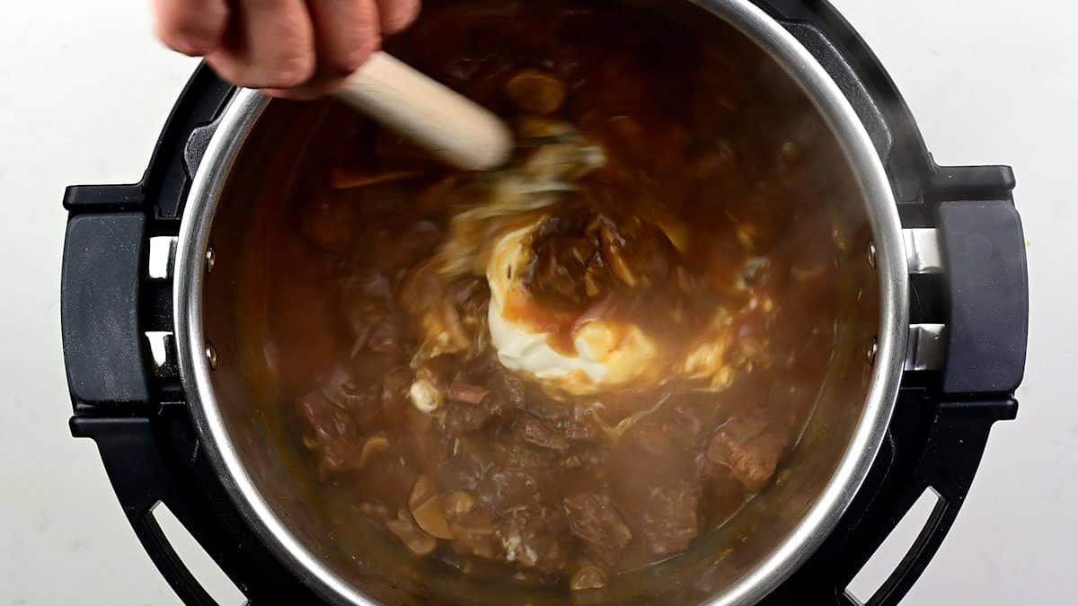 stirring sour cream into stroganoff sauce