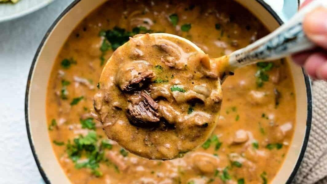 Close up on a ladle with creamy beef stroganoff
