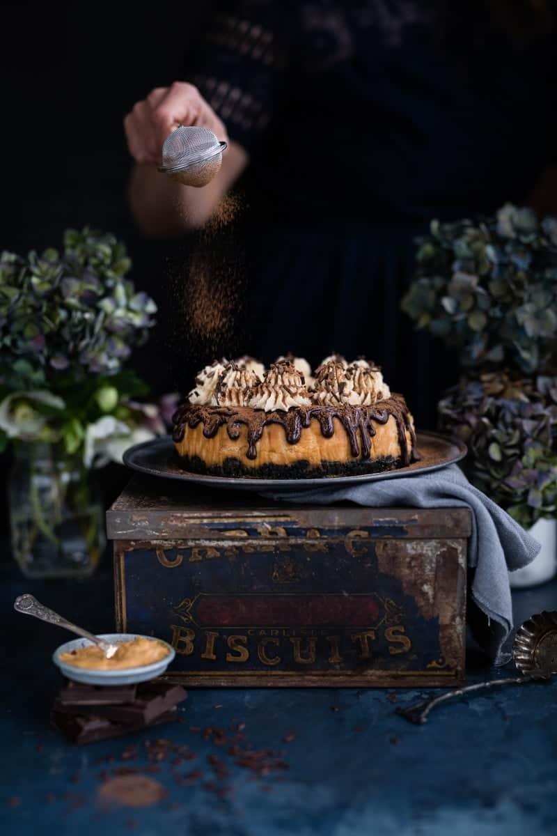 Peanut butter and caramel cheesecake dusted with cocoa powder