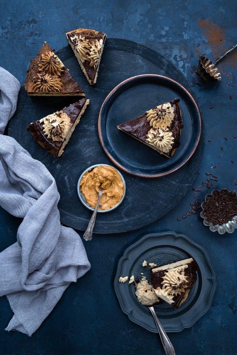 Slices of peanut butter caramel cheesecake topped with chocolate ganache and caramel whipped cream