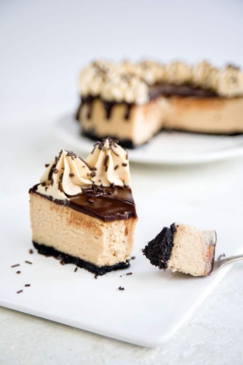 Slice of Instant Pot peanut butter caramel cheesecake topped with chocolate ganache and caramel whipped cream