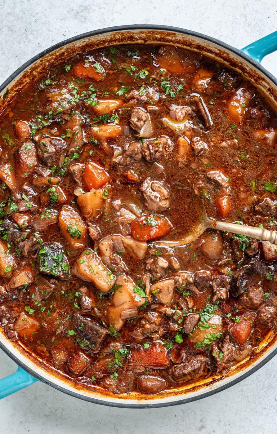 close up on Irish Lamb Stew in a cast iron casserole, large spoon resting in the gravy