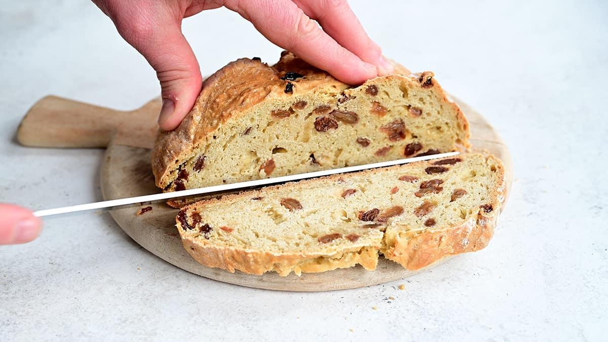 Slicing traditional Irish soda bread with raisins