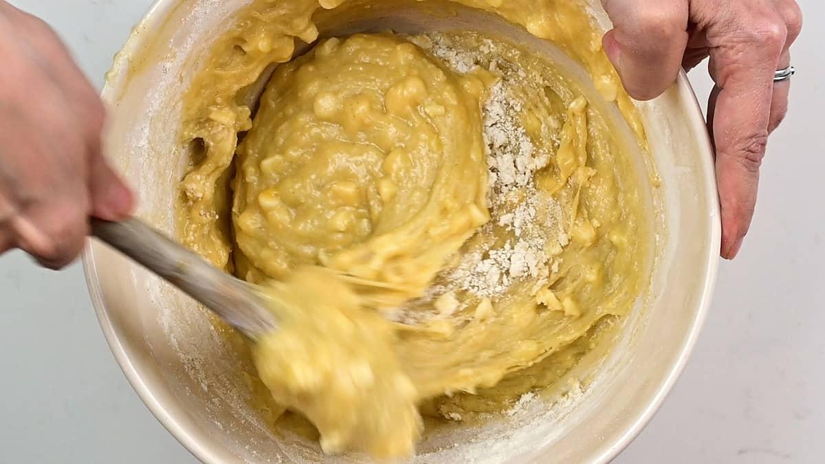 Stirring blondie batter with a wooden spoon in a mixing bowl