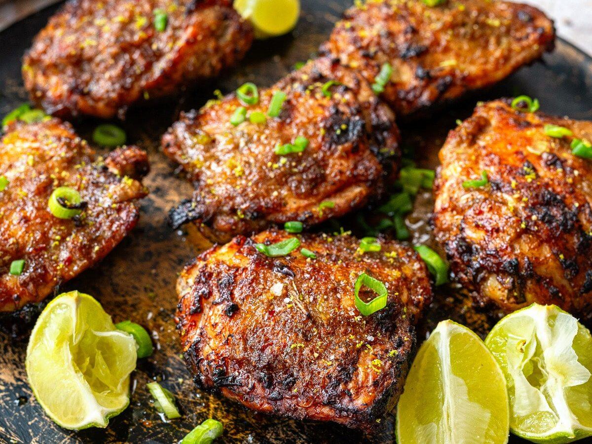 Plate of Jamaican Jerk Chicken thighs cooked in an air fryer, lime wedges on a the side