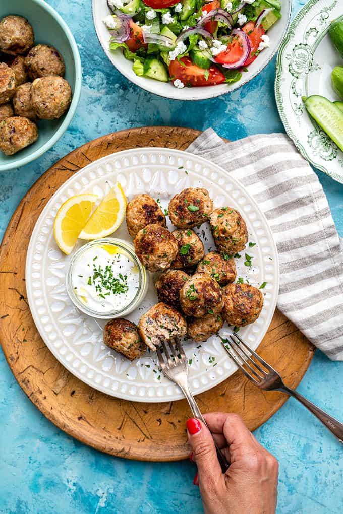 Overhead shot of a Greek turkey meatballs served with tzatziki and lemon wedges