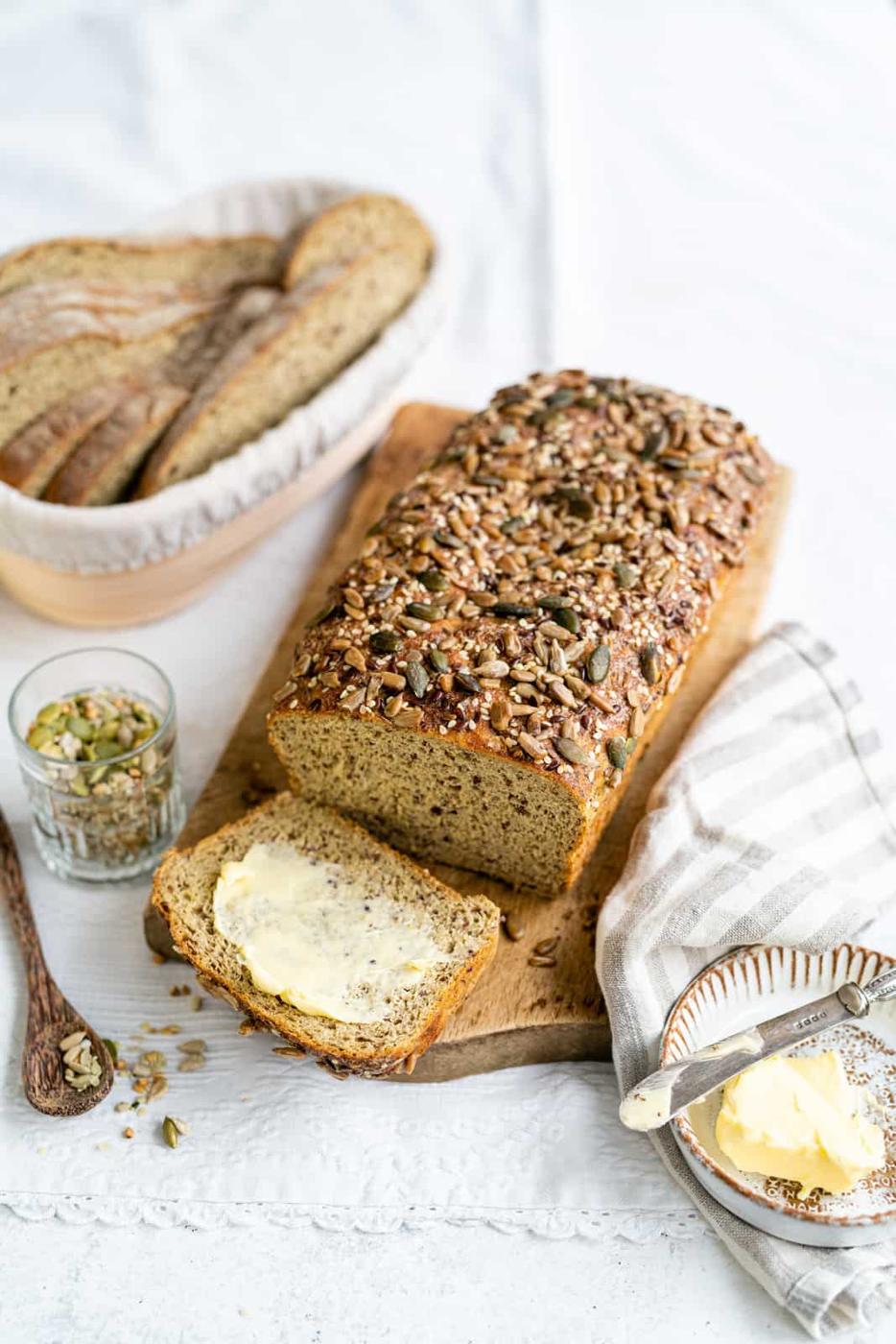 Low Carb bread topped with mixed seeds on a cutting board with slice cut out