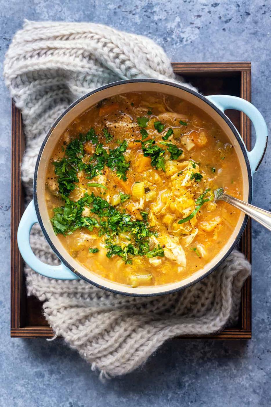 Pot of Keto Chicken soup garnished with chopped parsley and lemon zest