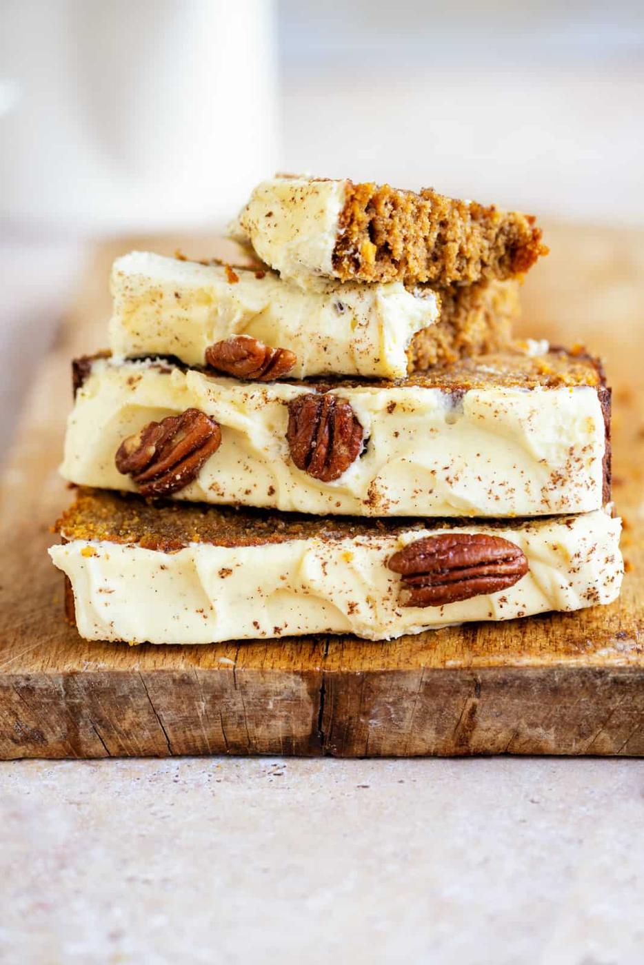 Three slices of gluten free pumpkin loaf stacked on a wooden board