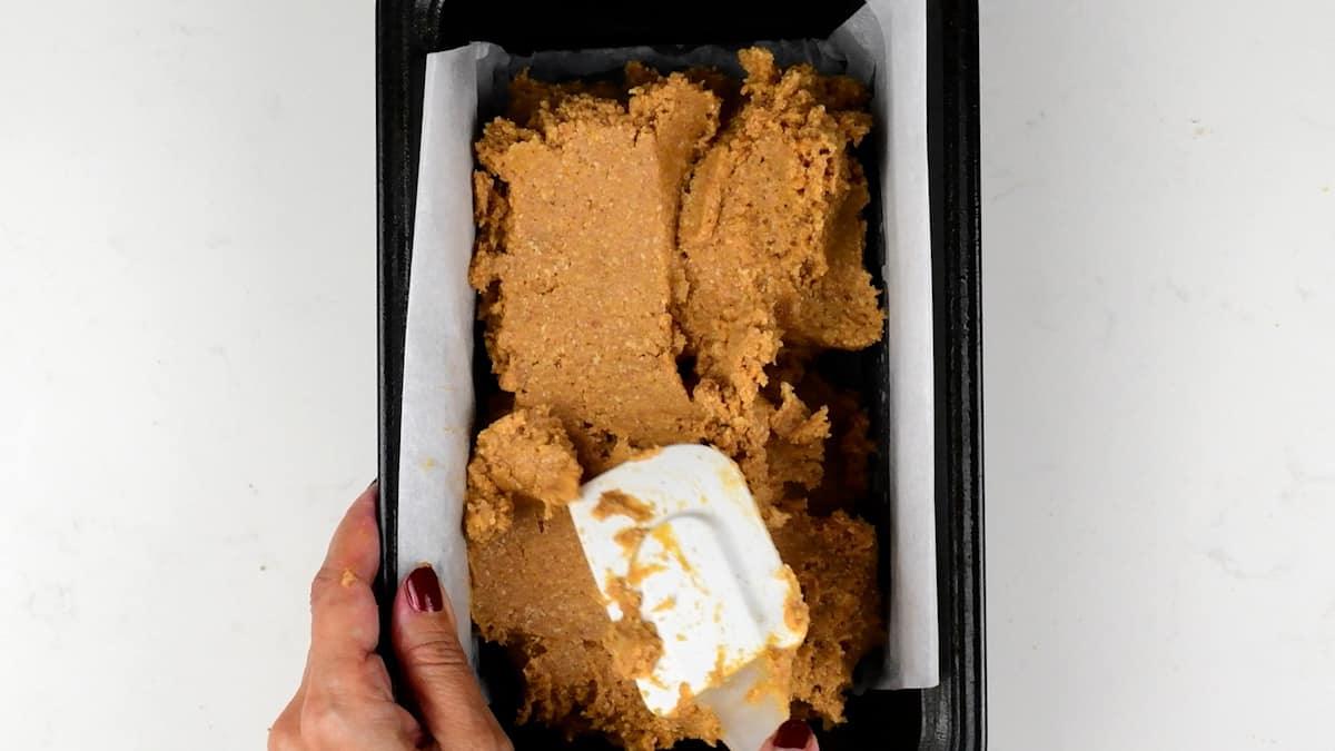 Spooning low carb pumpkin bread batter into a loaf tin