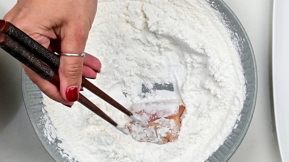 tossing chicken pieces in crispy coating before frying