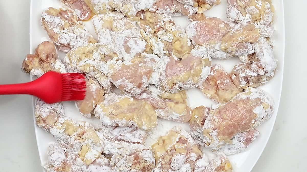 brushing breaded chicken pieces with oil