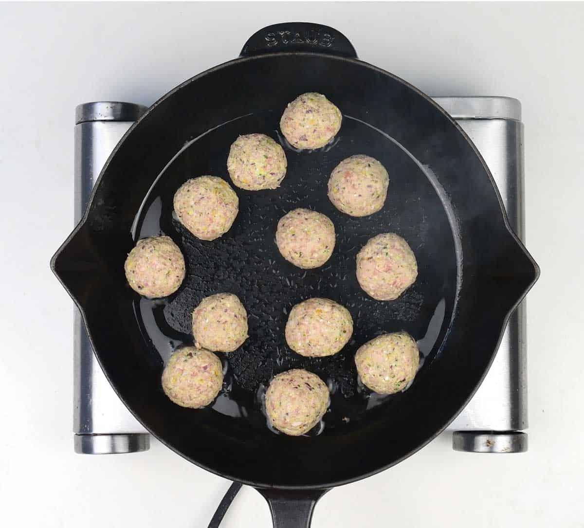 meatballs frying in a skillet