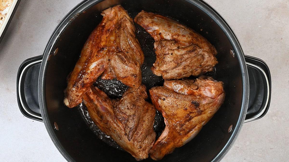 four browned lamb shanks in a crock pot
