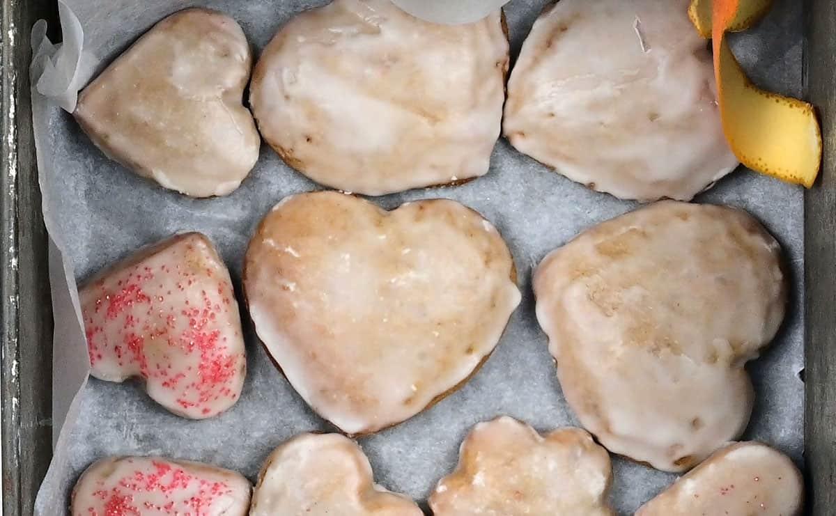 Layering christmas cookies in a tin with strips of orange peel