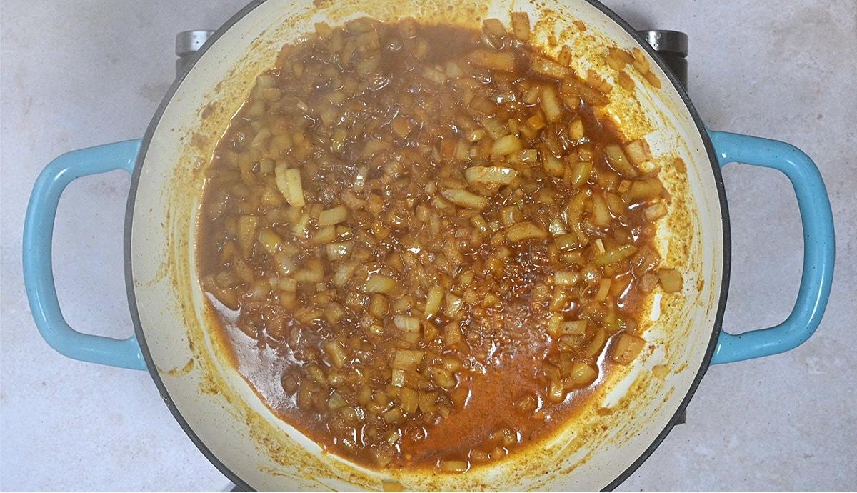 onions cooking with spices in a casserole dish