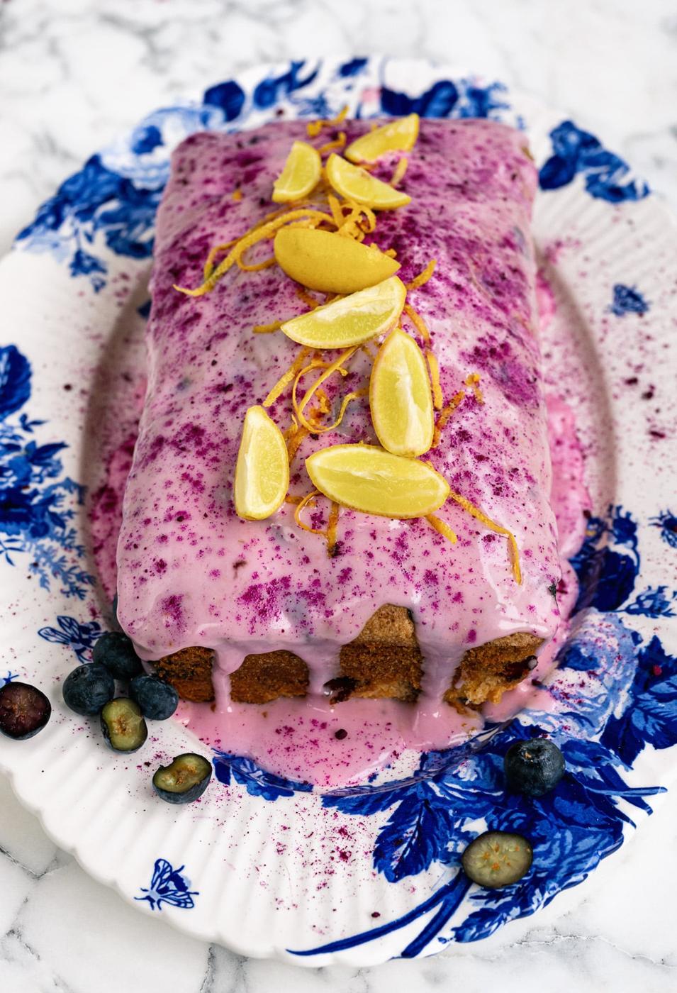 loaf cake with lemons and blueberries on a white and blue patterned plate