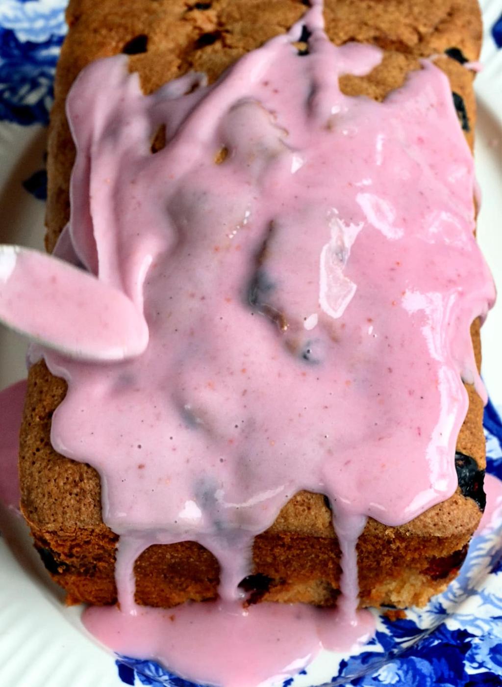 adding glaze over a blueberry lemon loaf cake