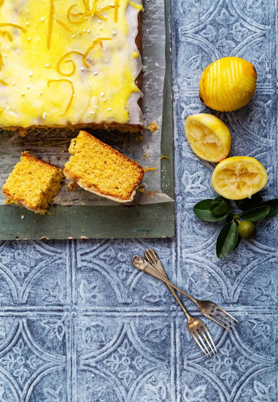 lemon drizzle traybake, sliced, with juiced lemons on the side