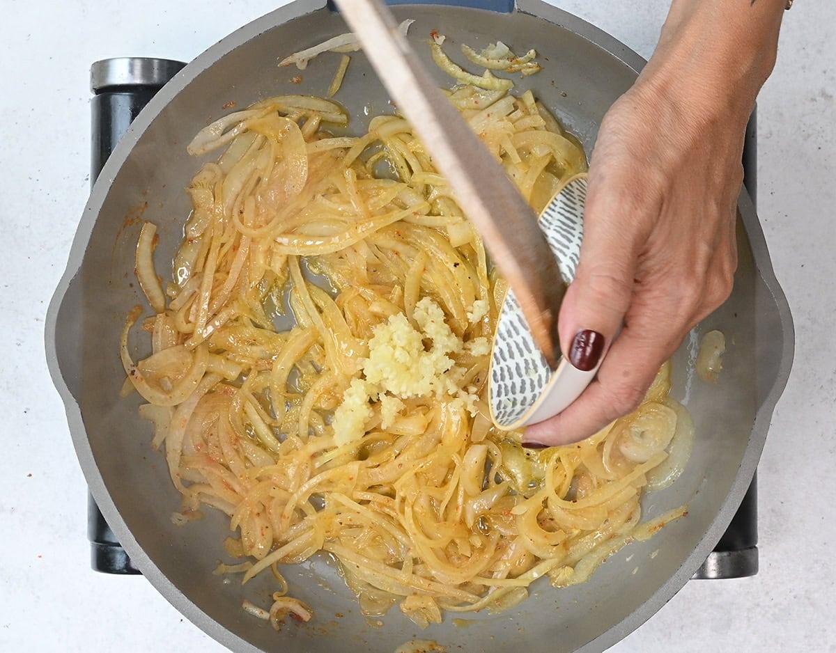 sliced onion and minced garlic cooking in a pan