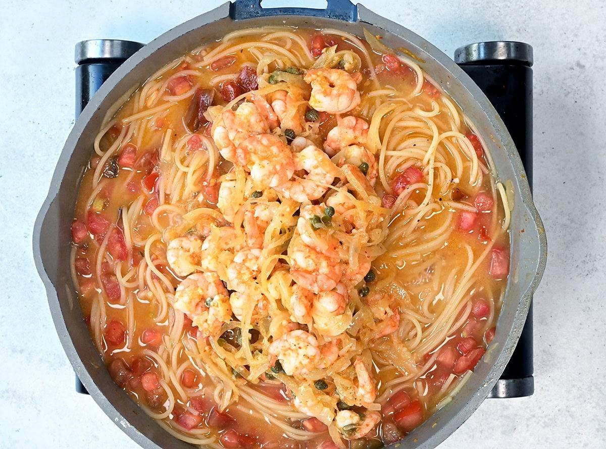 shrimp spaghetti with fresh diced tomatoes cooking in a pan