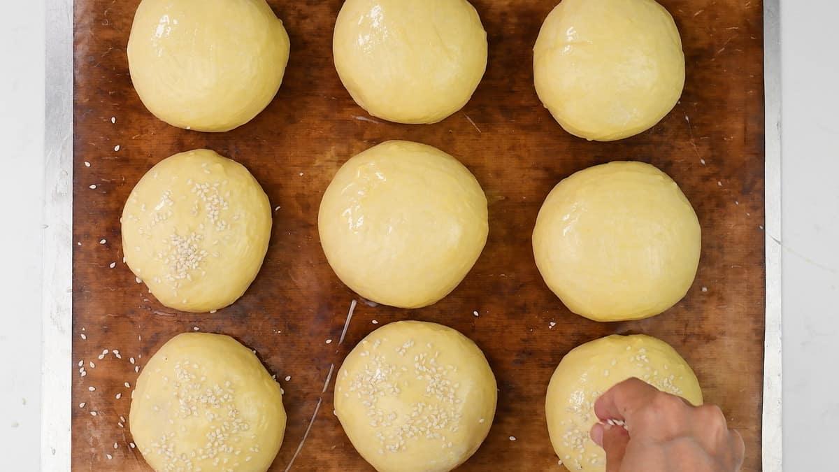 sprinkling burger buns with sesame seeds