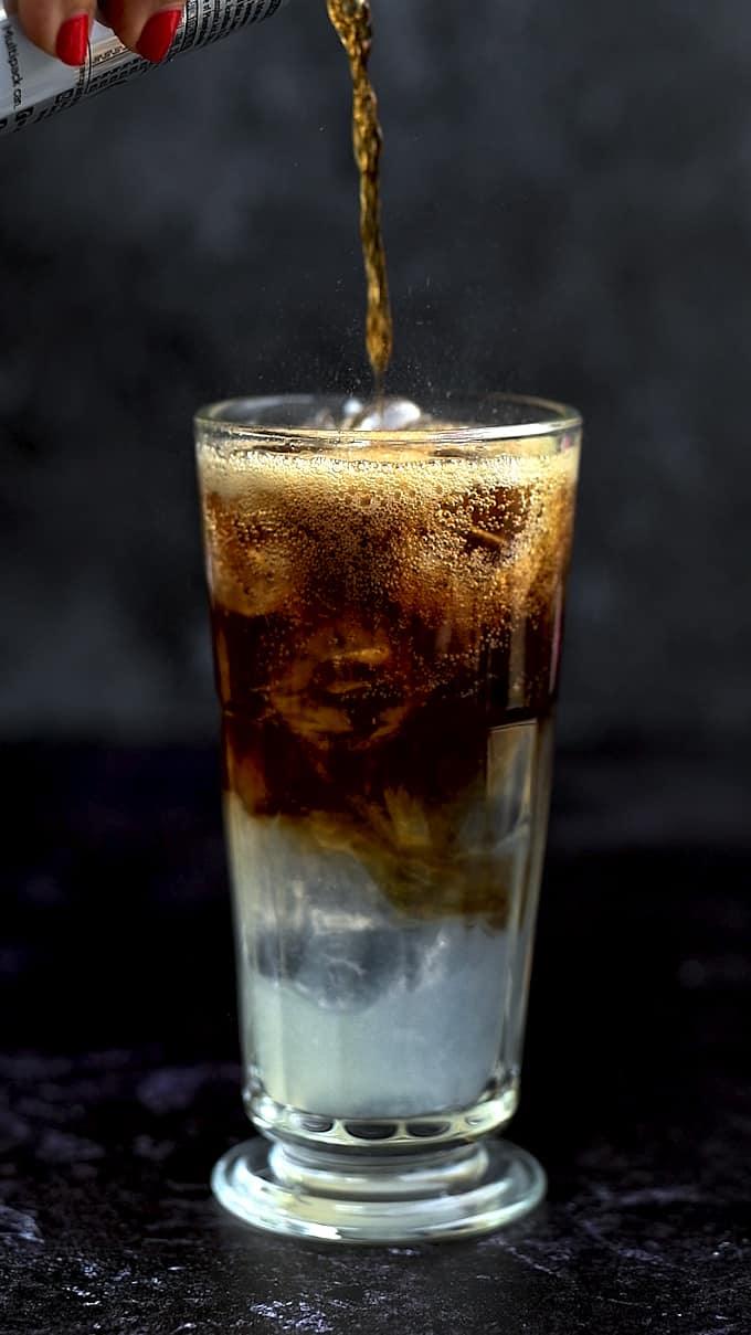 Topping a glass of Long Island drink with cola