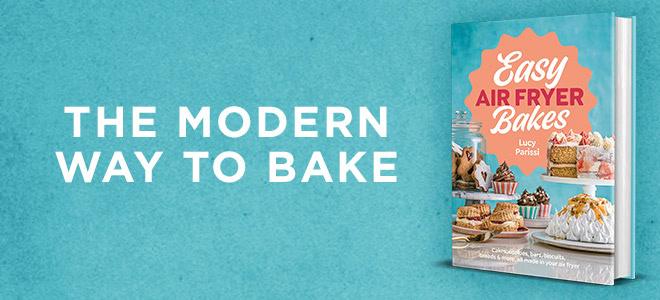 A cookbook titled Easy Air Fryer Bakes by Lucy Parissi of Nusde sits upright on a blue background. The cover displays various baked desserts. Next to the book, text reads: THE MODERN WAY TO BAKE.