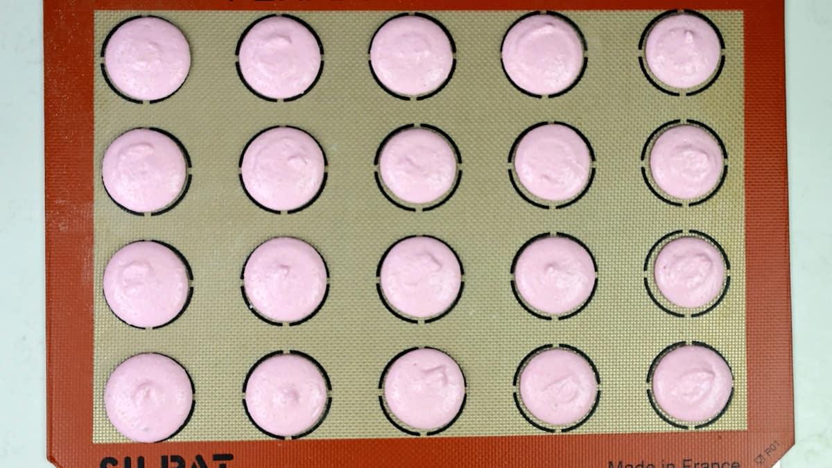 knocking a tray of macaron shells against kitchen counter to release air bubbles