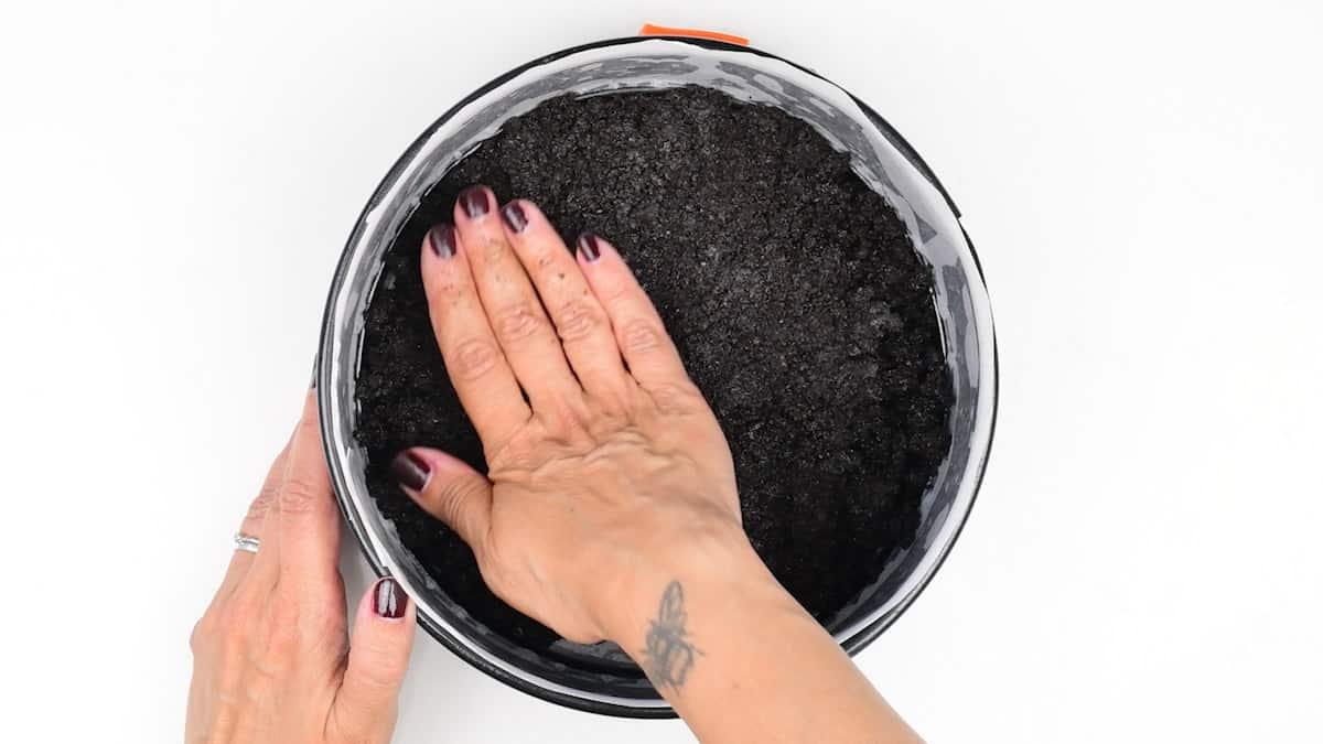 Pressing cookie crumbs into springform cake tin to make cheesecake base