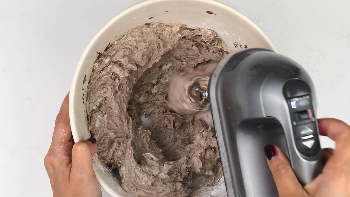 Beating ingredients for malt cheesecake in a bowl with an electric hand mixer