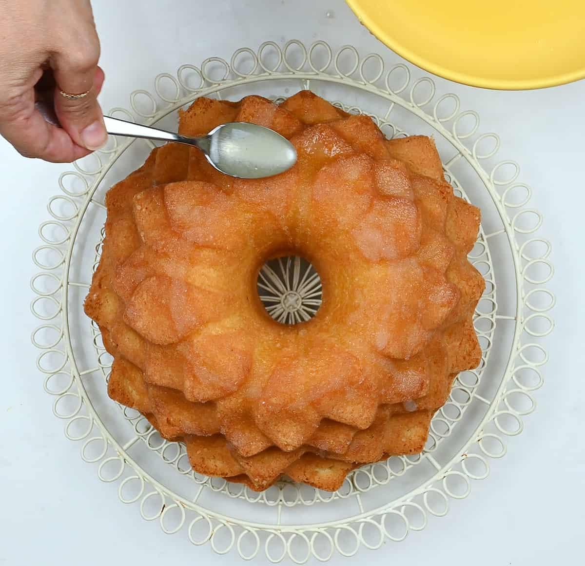 adding lemon drizzle over lemon bundt cake