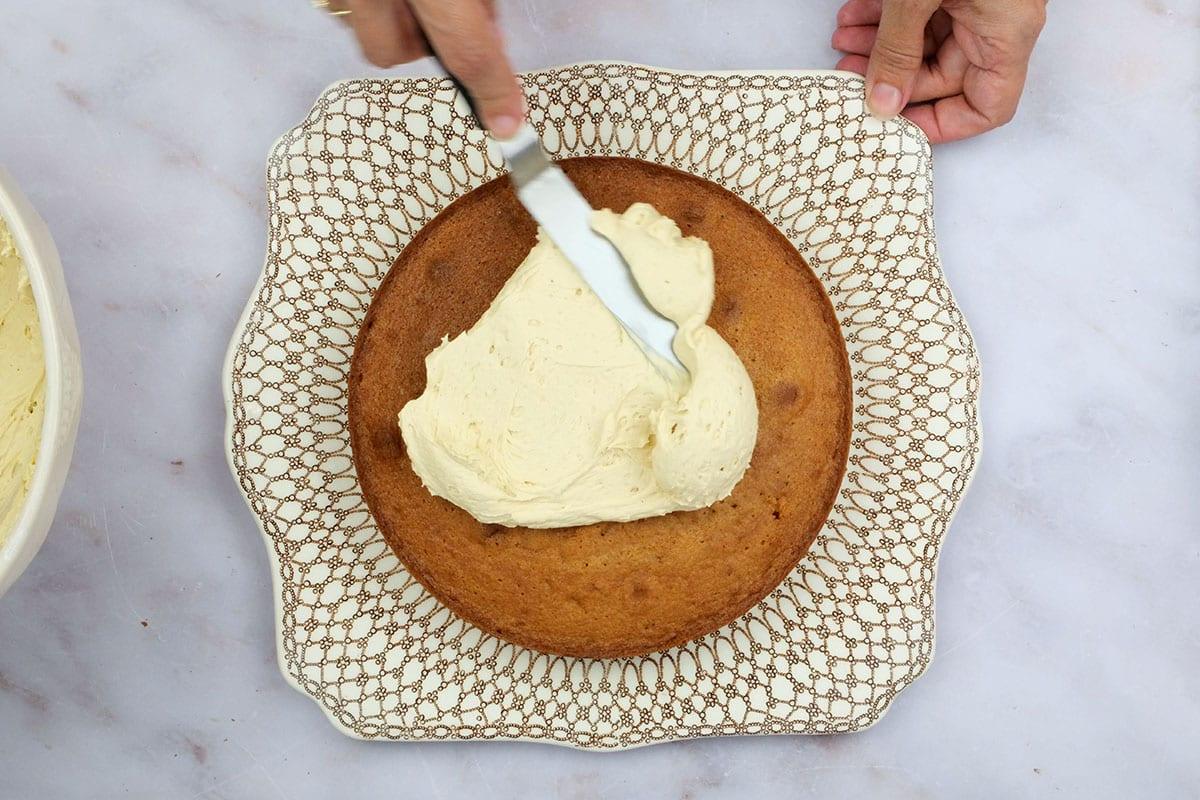 spreading caramel buttercream over caramel cake