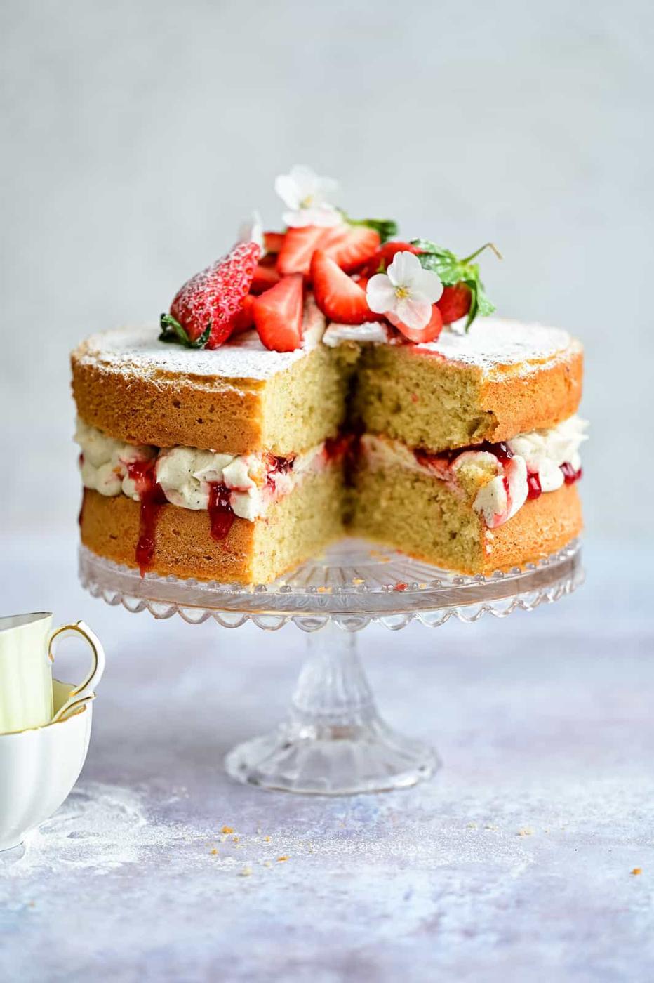 Victoria cake with slice taken out on a cake stand