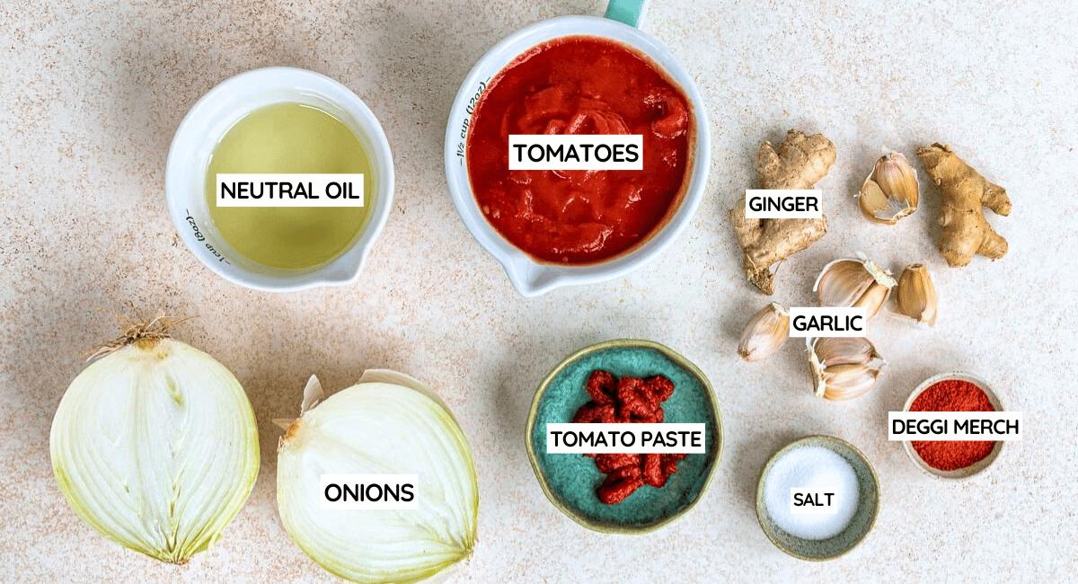 Ingredients for a flavourful Masala Sauce are arranged on a light surface, including neutral oil, tomatoes, ginger, garlic, halved onions, tomato purée, red chilli powder labelled deggi mirch, and salt.