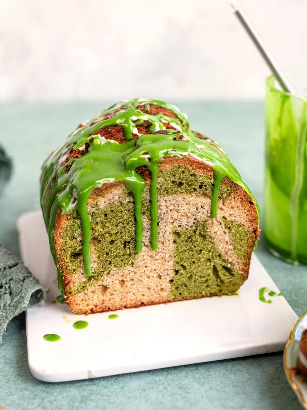 A slice of marbled matcha banana bread drizzled with green matcha icing.