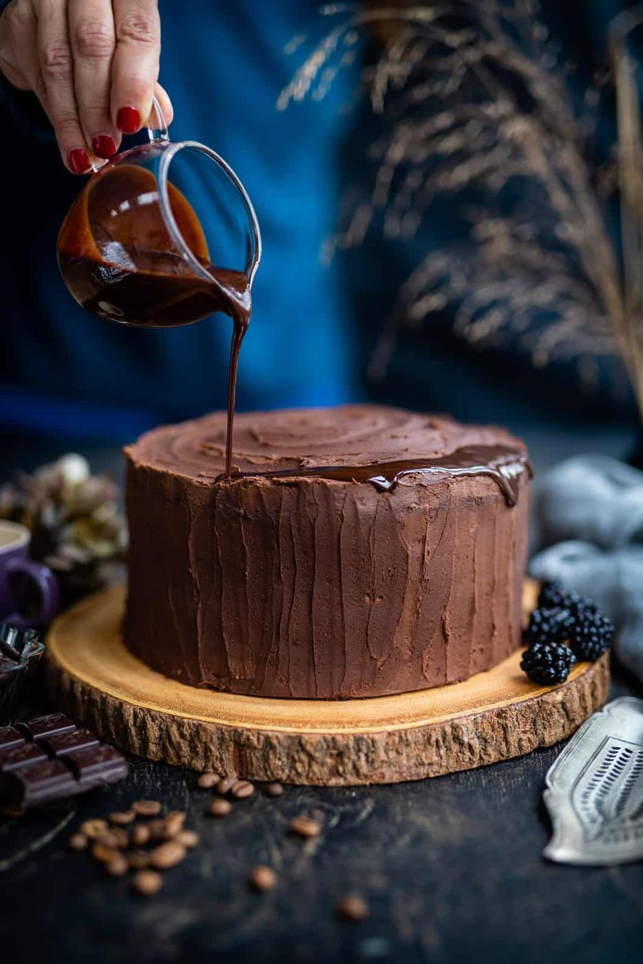 Adding a chocolate drip on a frosted chocolate cake