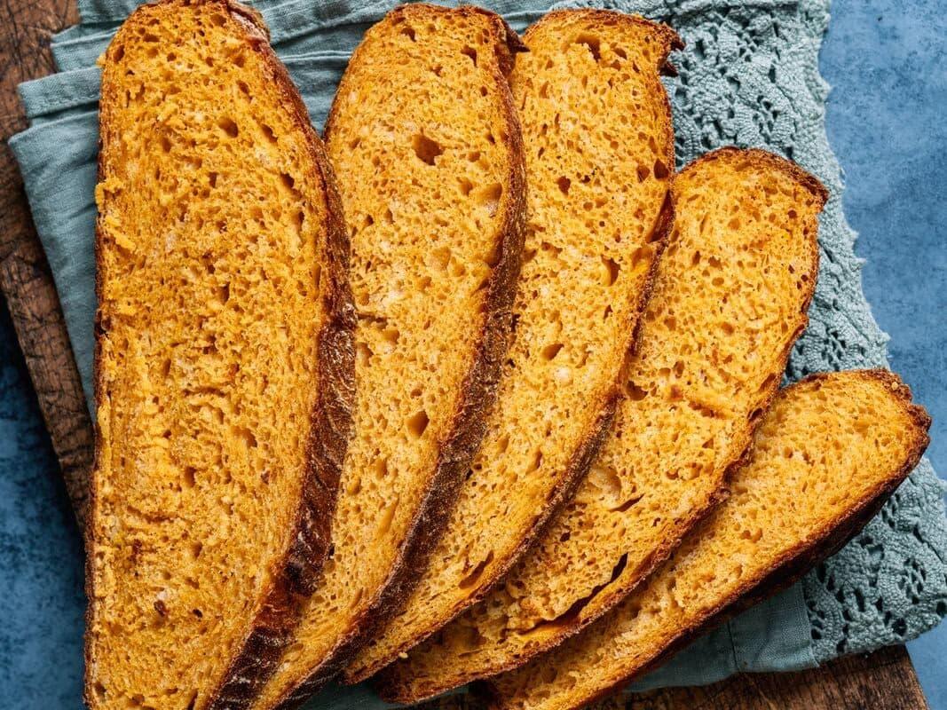 sliced pumpkin bread on a cutting board, small butter dish on the side