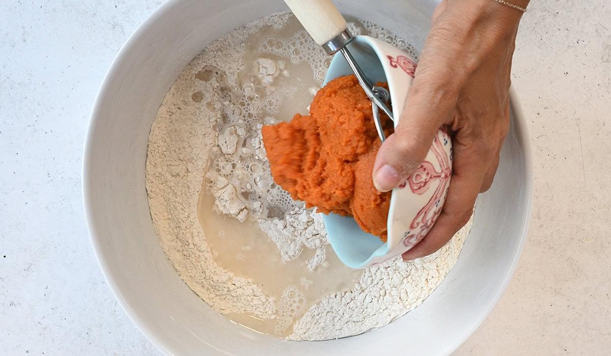 ingredients for pumpkin bread being added into a mixing bowl