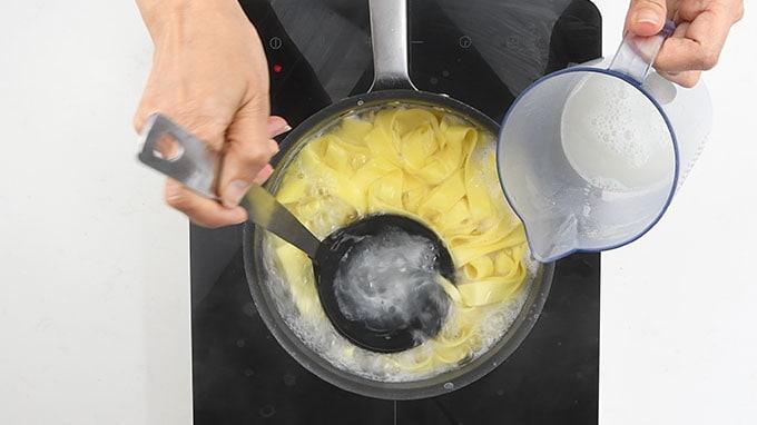 reserving pasta water from a pot of fettucine